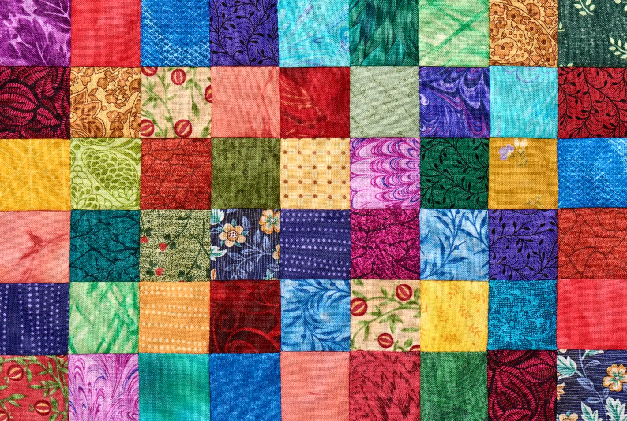Colorful detail of quilt sewn from square pieces
