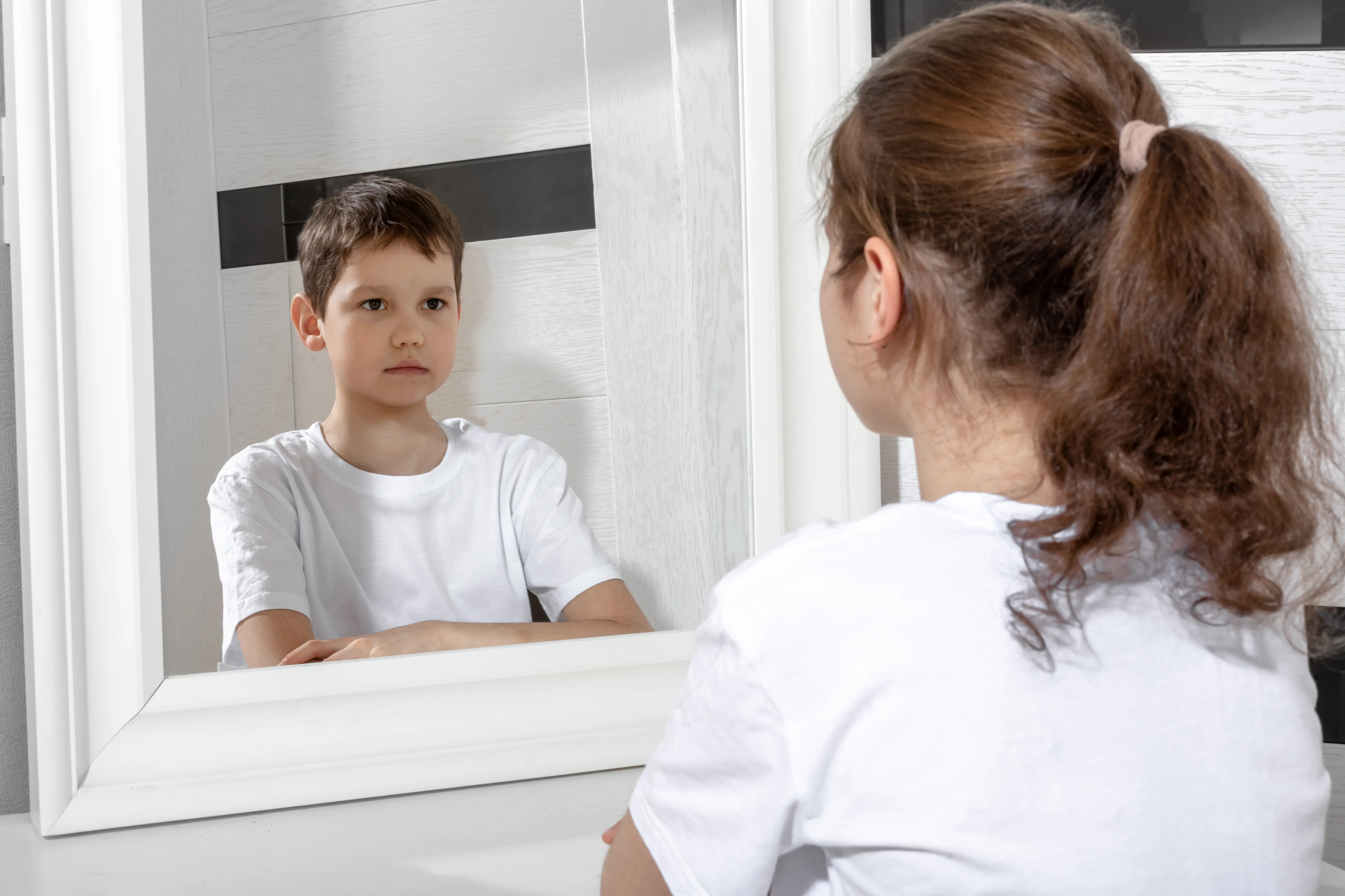 girl looking in mirror and seeing boy - concept of transgenderism