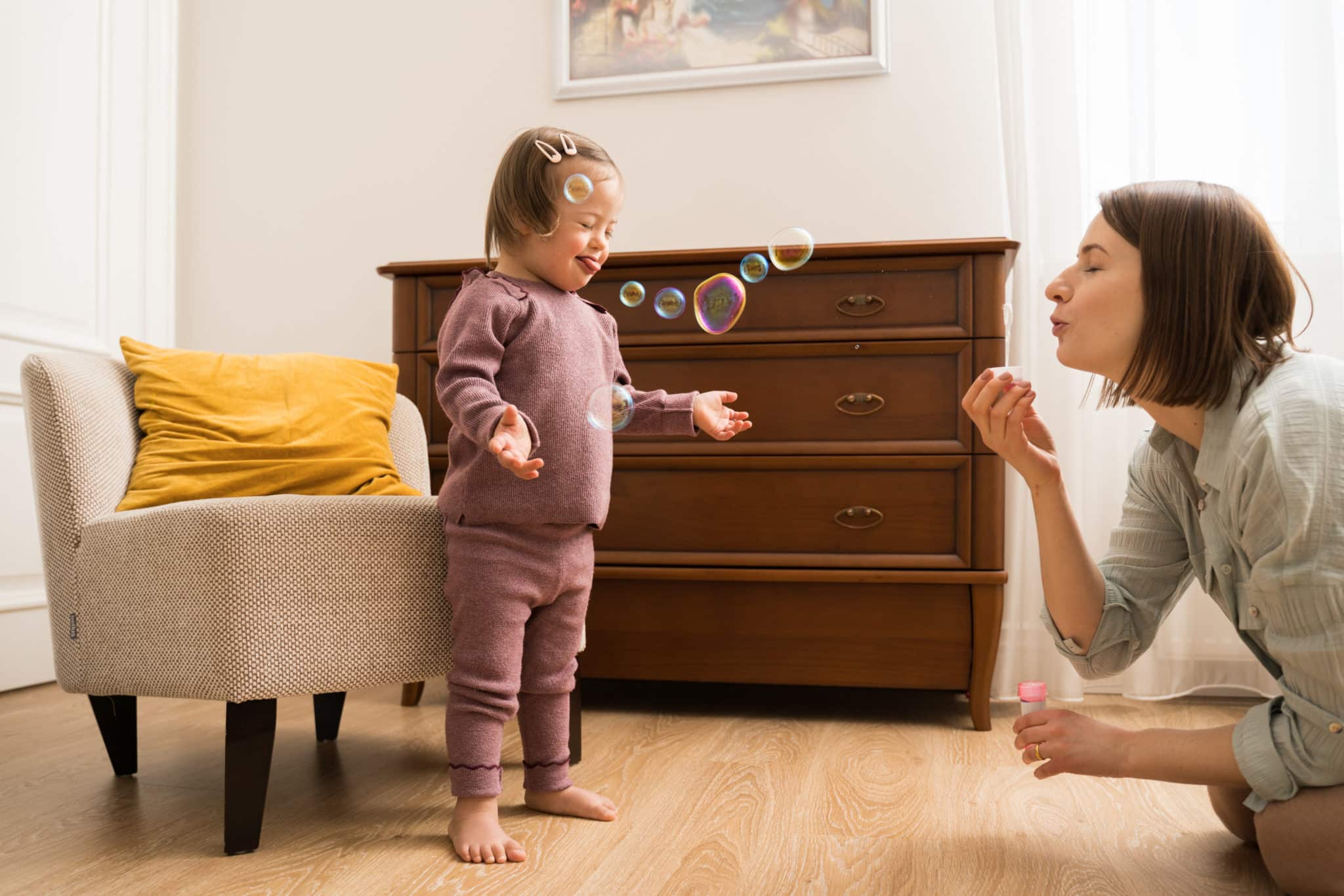 mom blowing bubbles at her daughter with down syndrome