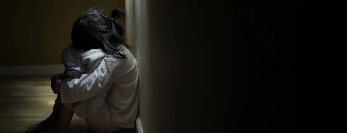 unhappy little girl sitting in a dark hallway