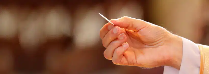 the hand of a priest distributing holy Communion