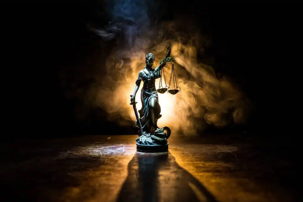 Law concept. Miniature colorful artwork decoration with fog and backlight. The Statue of Justice - lady justice or Iustitia / Justitia the Roman goddess of Justice. Selective focus.The Statue of Justice - lady justice or Iustitia / Justitia the Roman goddess of Justice on a dark fire background
