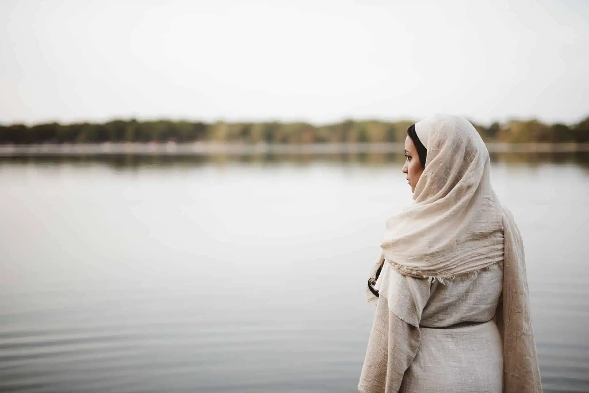 A shallow focus shot from behind of a female wearing a biblical gown while looking in the distance