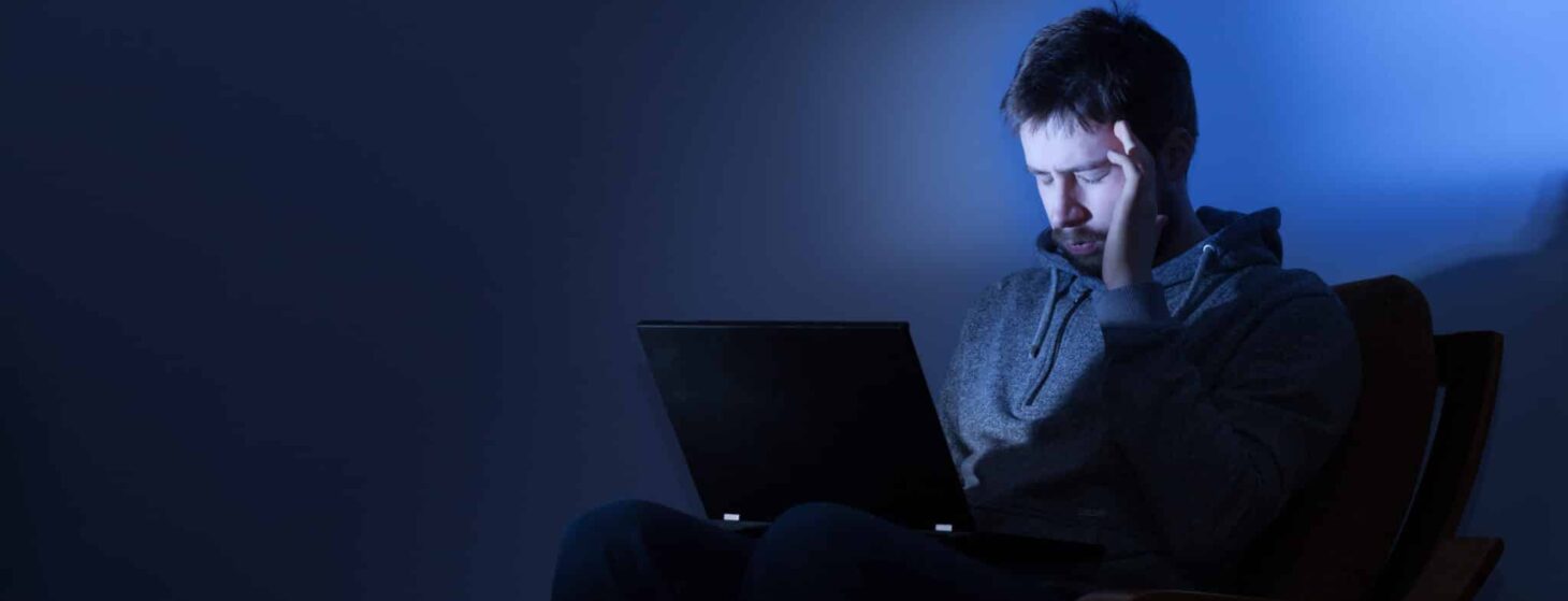 Man on a laptop in a dark room at night