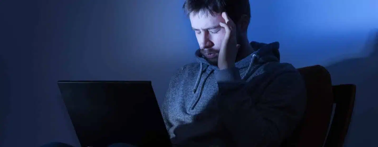 Man on a laptop in a dark room at night