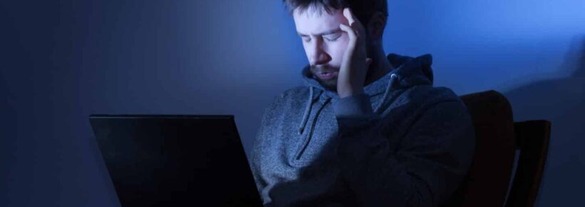 Man on a laptop in a dark room at night