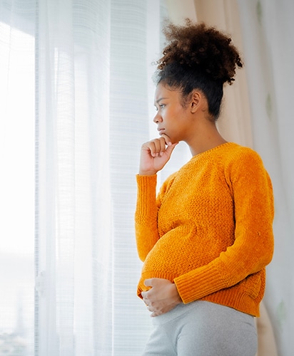 Arican American pregnancy woman in yellow sweater put hand under chin and hold her belly with thinking, worry emotion with copy space.