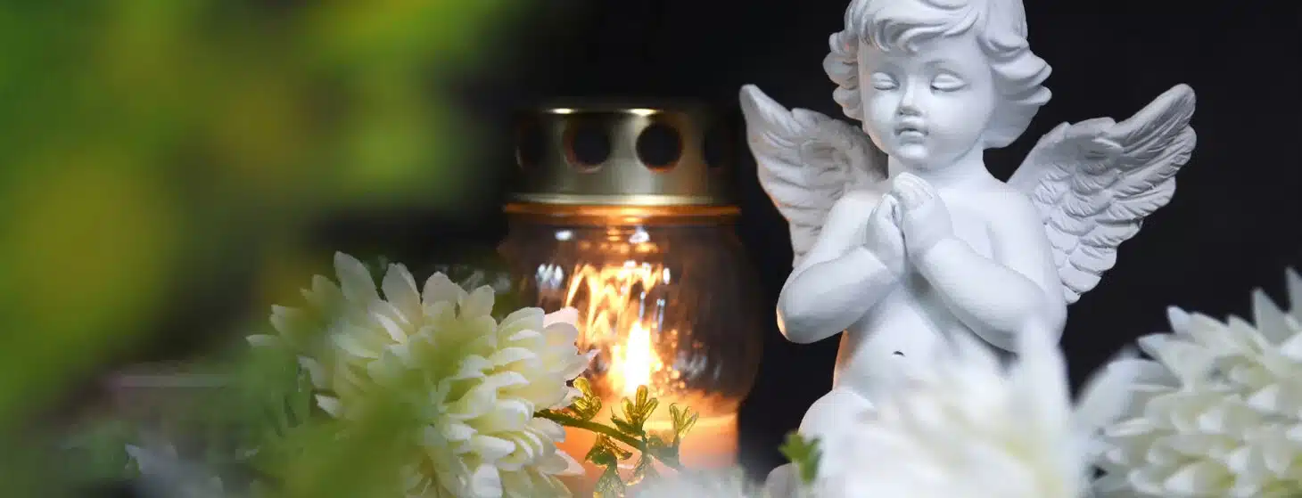 baby angel statue with candle and flowers