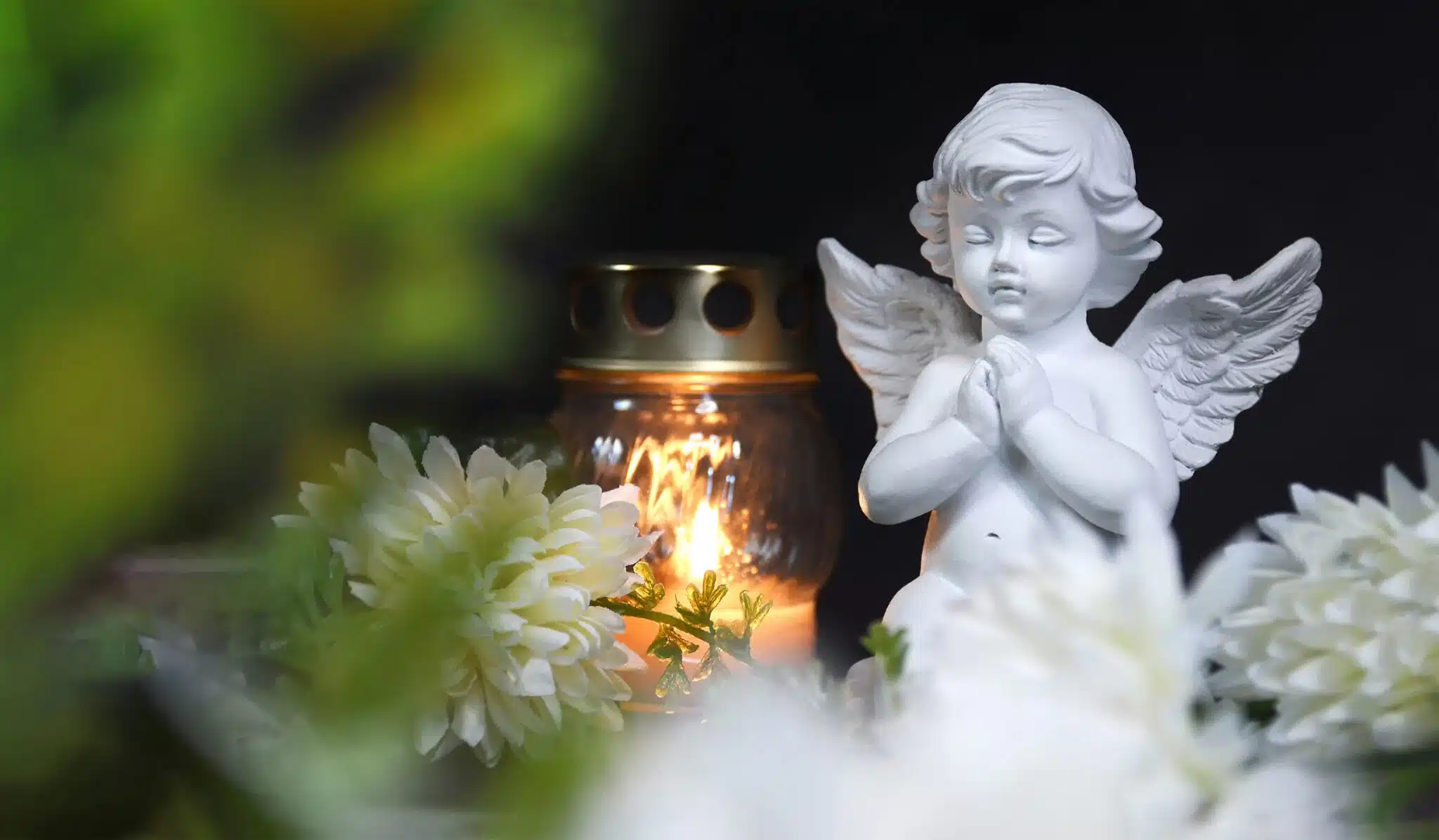 baby angel statue with candle and flowers