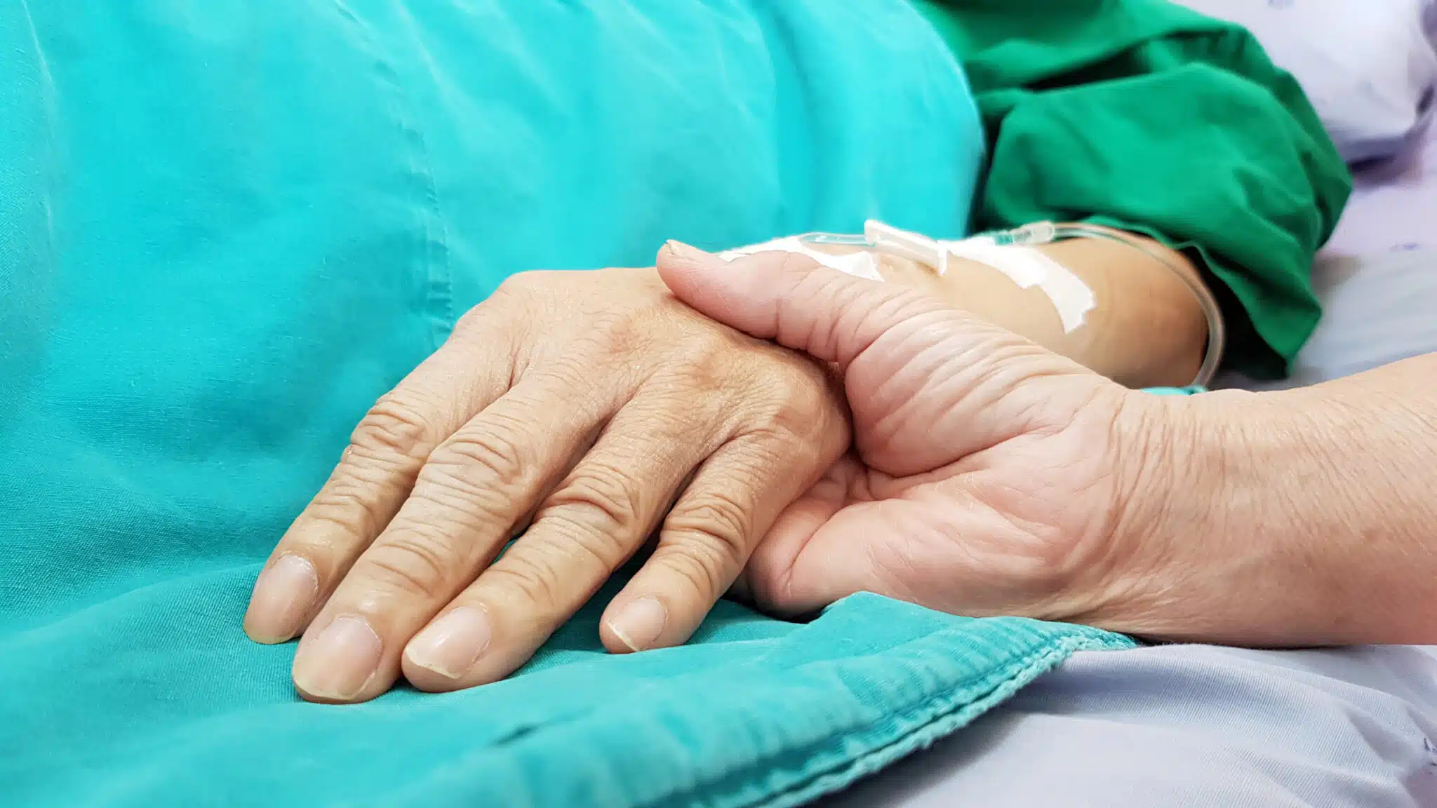 person holding patient's hand in hospital