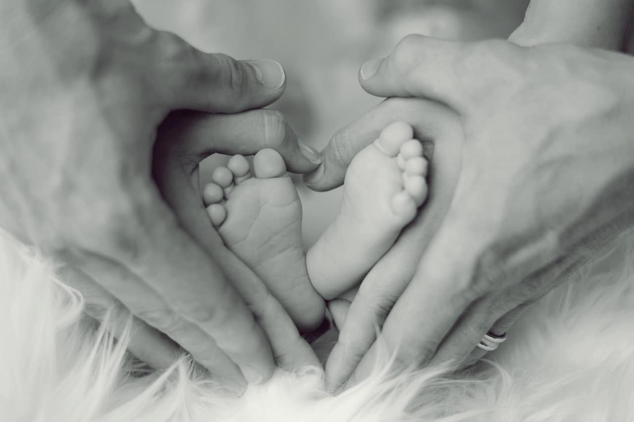 parents hands and baby feet forming heart