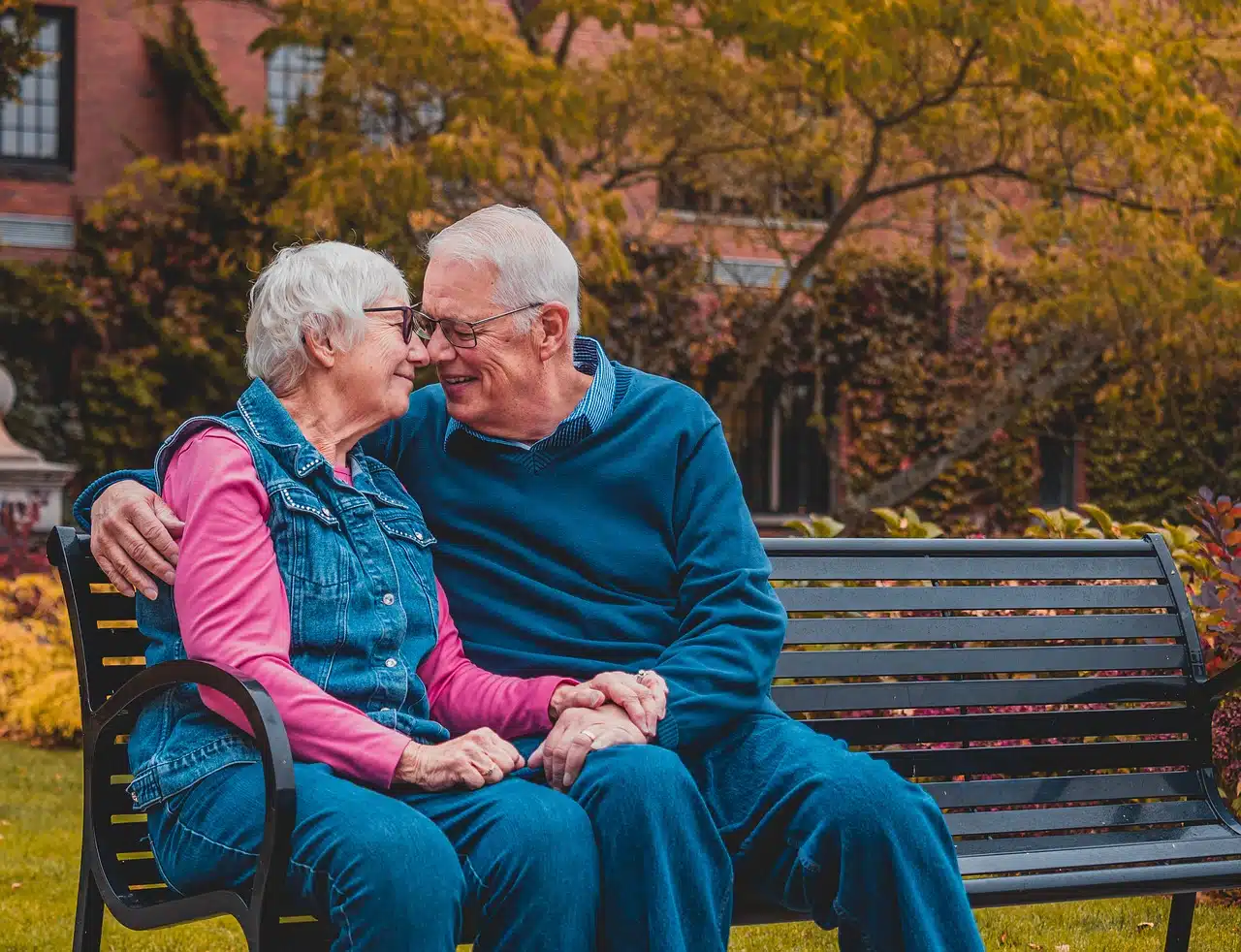 elderly couple sitting on park bench