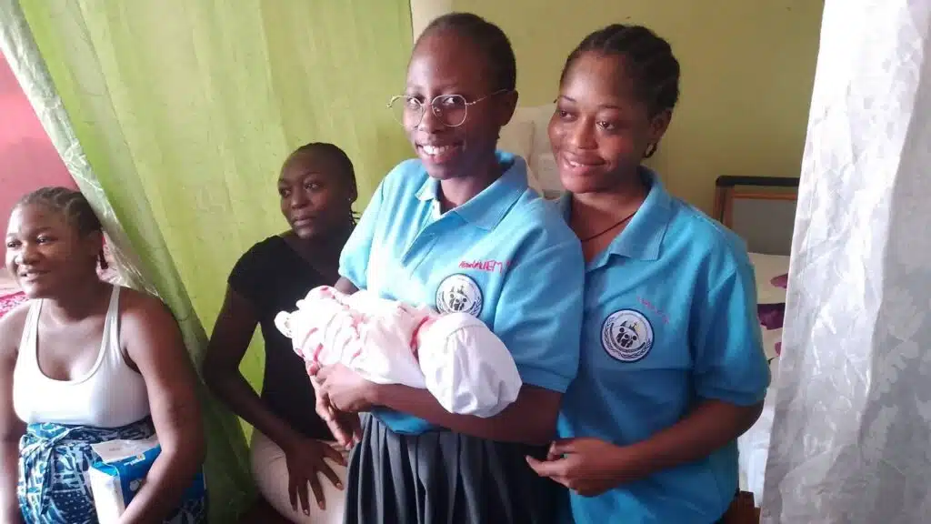 Highschool students holding a newborn in a hospital in Cameroon